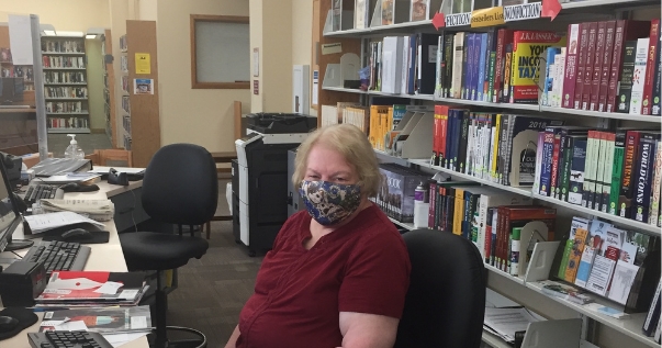 adult services employee at desk with mask on 